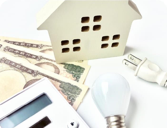 住宅模型と電卓、LED電球。光熱費・資産価値のイメージ